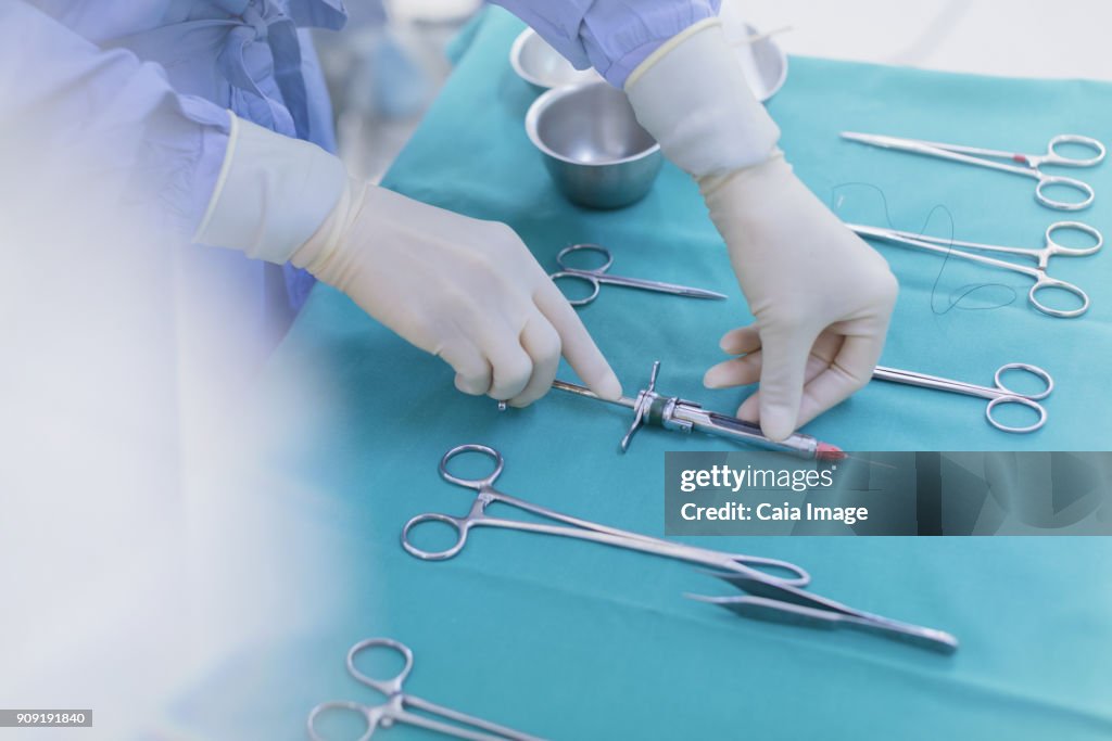 Surgeon in rubber gloves preparing surgical instruments on tray