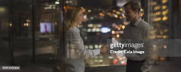 businessman and businesswoman handshaking in office at night - first exposure series stock pictures, royalty-free photos & images