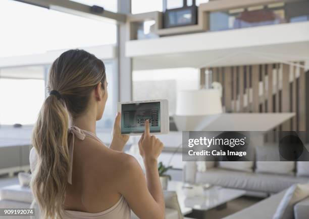 woman with digital tablet setting digital security system in modern, luxury home showcase interior living room - security code stock pictures, royalty-free photos & images