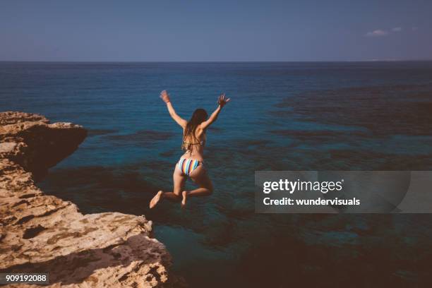 joven saltando del acantilado y buceo en mar azul - salto desde acantilado fotografías e imágenes de stock