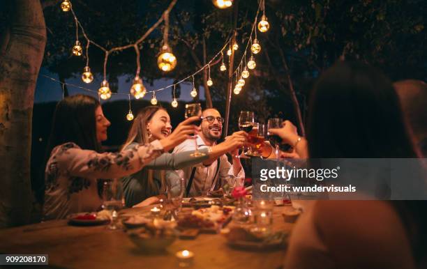friends toasting with wine and beer at rustic dinner party - dining stock pictures, royalty-free photos & images