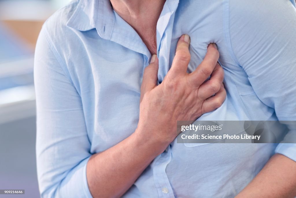 Woman clutching her chest, cropped view