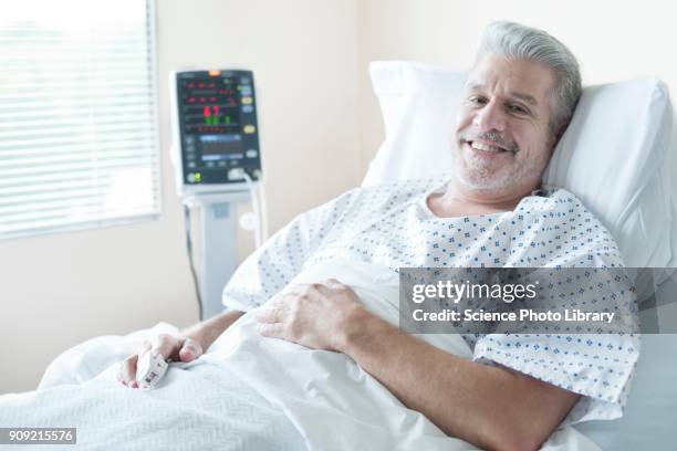 mature male patient in hospital bed, smiling - adult male hospital bed stock-fotos und bilder