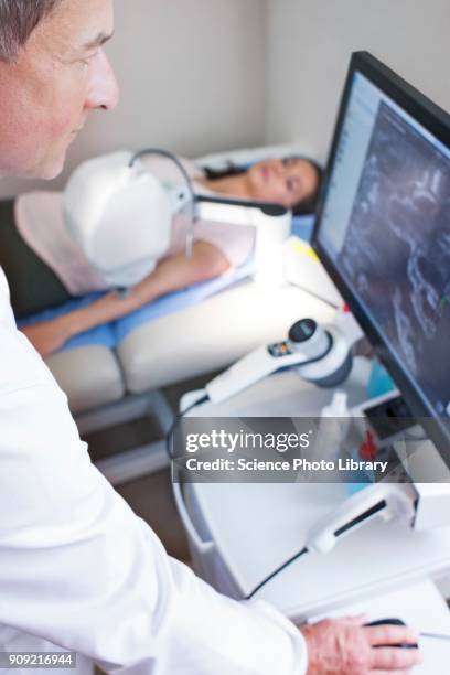 doctor looking at computer monitor, patient on bed - stratum corneum imagens e fotografias de stock