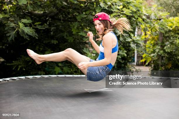 woman bouncing on trampoline - trampoline equipment stock-fotos und bilder