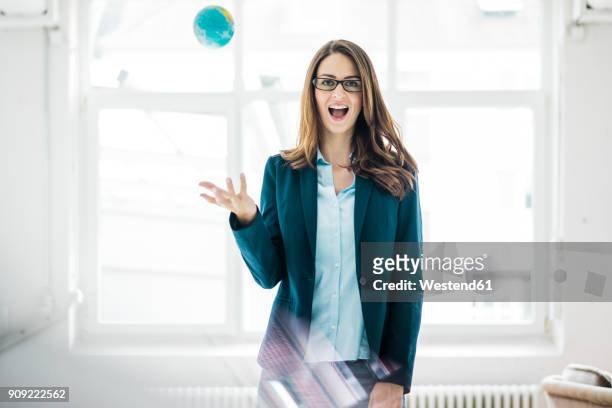 portrait of businesswoman throwing small globe in the air - woman effortless stock pictures, royalty-free photos & images