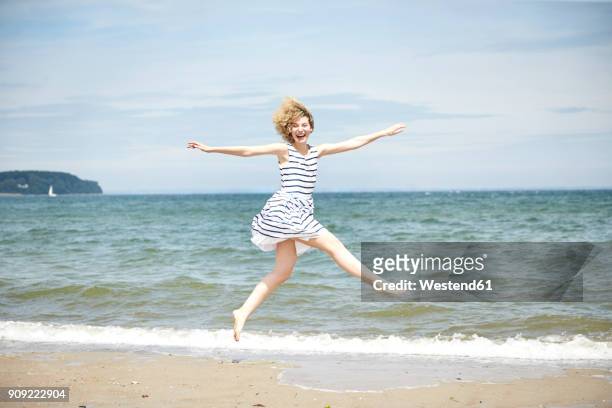 happy young woman jumping in the air in front of the sea - schleswig holstein stock pictures, royalty-free photos & images