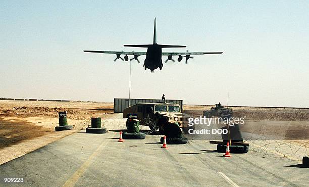 Hercules transport aircraft loaded with troops from the 101st Airborne Division takes off during Operation Desert Storm. Behind the highway barricade...