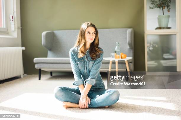 young woman sitting on the floor in the living room - cross legged stock pictures, royalty-free photos & images