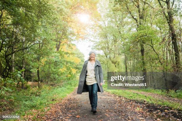 portrait of happy woman walking in the forest in autumn - front on portrait older full body foto e immagini stock