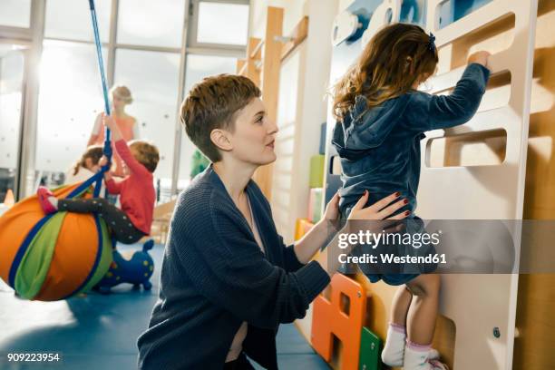 pre-school teacher helping little girl climbing up a wall - teacher pre school bildbanksfoton och bilder