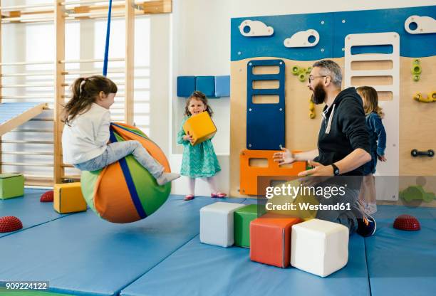 pre-school teacher and happy children playing in gym room in kindergarten - kindergartengebäude stock-fotos und bilder
