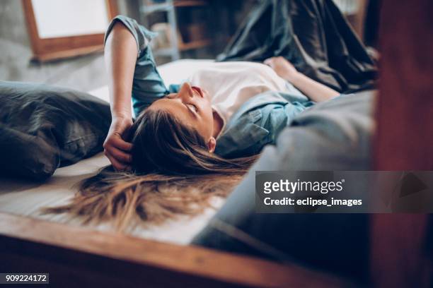 young women laying on bed - pms stock pictures, royalty-free photos & images