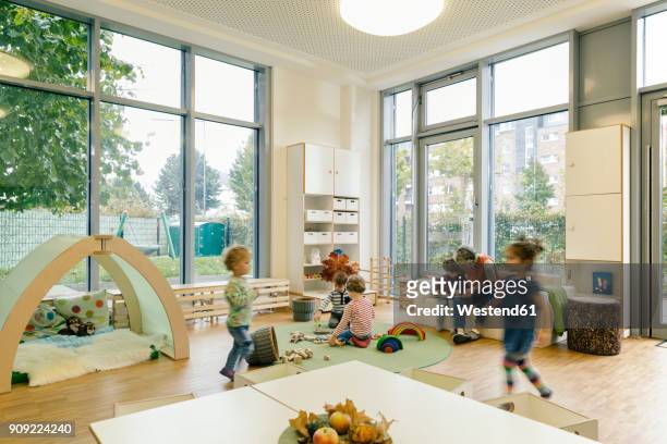 pre-school teacher and children in playing in learning room in kindergarten - kindergartengebäude stock-fotos und bilder