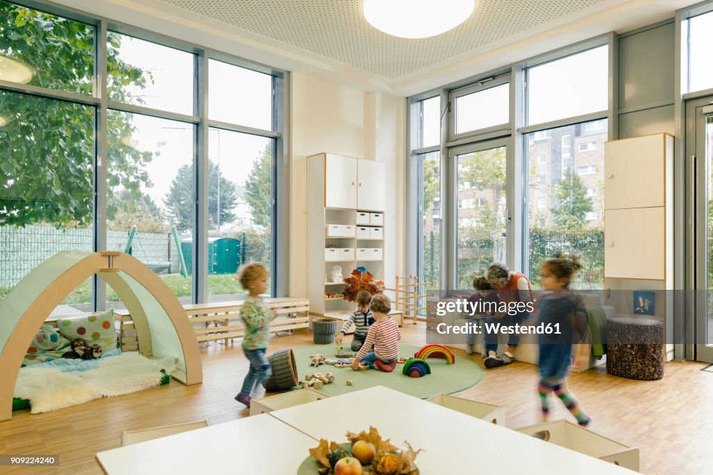 Pre-school teacher and children in playing in learning room in kindergarten