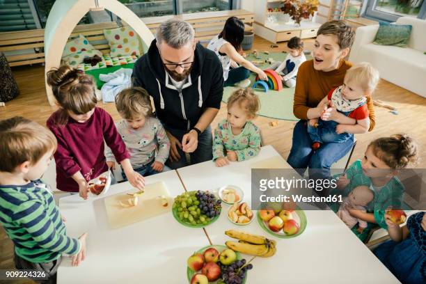 group of children and teachers preparing fruit in kindergarten - nursery school building stock pictures, royalty-free photos & images