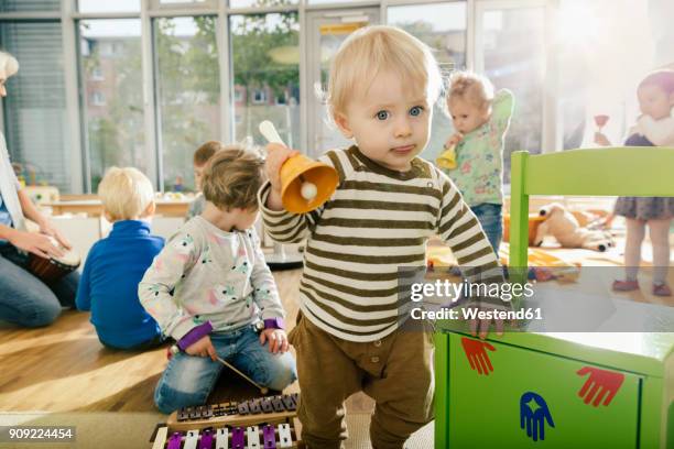 toddler ringing a bell in music room of a kindergarten - escuela preescolar fotografías e imágenes de stock