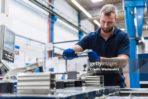 man working on machine in industrial factory - metallo stock-fotos und bilder