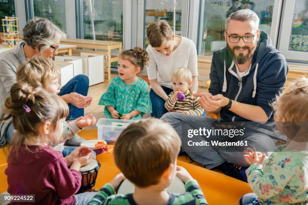 children and teachers playing and making music in kindergarten - bébé joue photos et images de collection