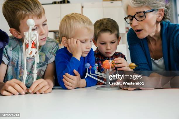 pre-school teacher explaining solar system model to boys in kindergarten - human skeletal system stockfoto's en -beelden