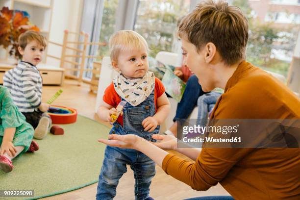 pre-school teacher playing with little boy in kindergarten - child care stockfoto's en -beelden
