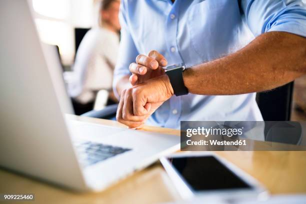 businessman checking smartwatch in office - mens wrist watch stockfoto's en -beelden