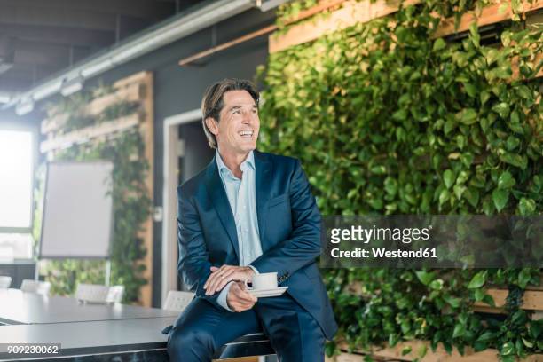 laughing businessman in green office with cup of coffee - green suit foto e immagini stock