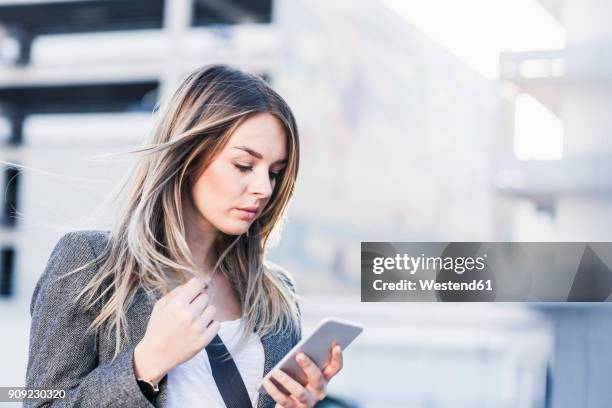 serious young woman checking cell phone outdoors - young adult mobile phone serious stock pictures, royalty-free photos & images