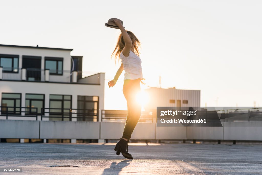 Happy young woman on parking level in the city at sunset