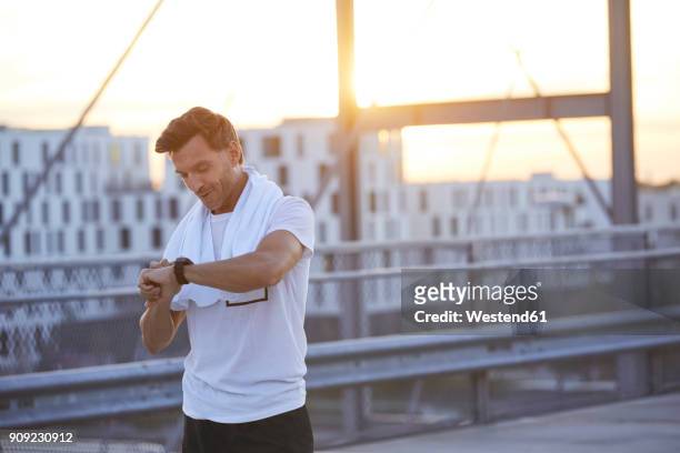 athlete in the city looking on smartwatch - after workout towel happy stock pictures, royalty-free photos & images