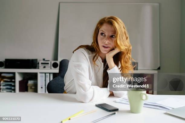 young woman with cup of coffee at desk in office - founders cup portraits fotografías e imágenes de stock