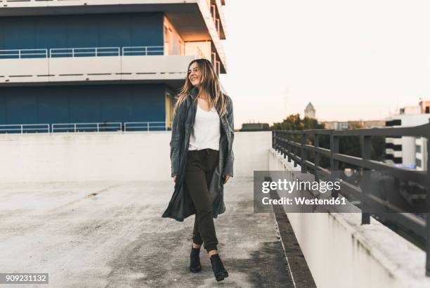 smiling young woman on parking level in the city - coat stock-fotos und bilder