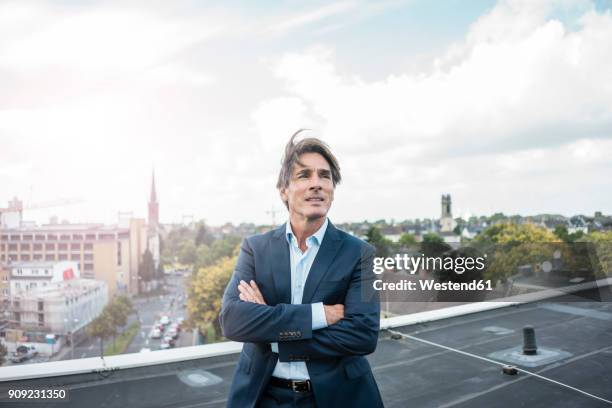 businessman standing on roof in the city - windy city stock pictures, royalty-free photos & images