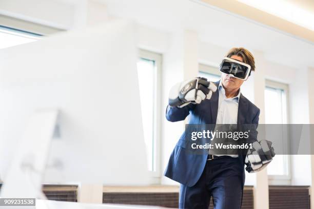 businessman wearing vr glasses and ice hockey gloves in office - weird hobbies stock pictures, royalty-free photos & images