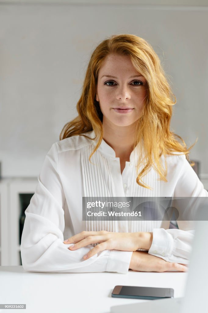 Portrait of confident young woman at desk in office
