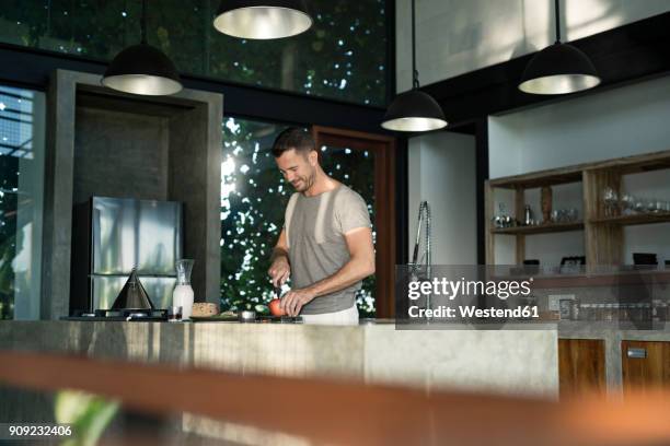 mature man standing in kitchen, preparing healthy breakfast - ein mann allein stock-fotos und bilder