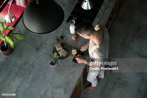 mature man standing in kitchen, preparing healthy breakfast - food styling stock-fotos und bilder