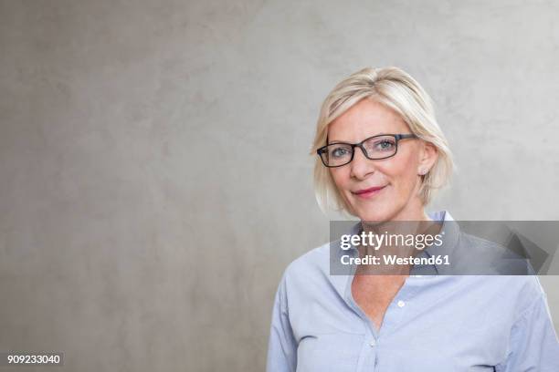 portrait of smiling senior woman wearing glasses - portrait grey background stock-fotos und bilder