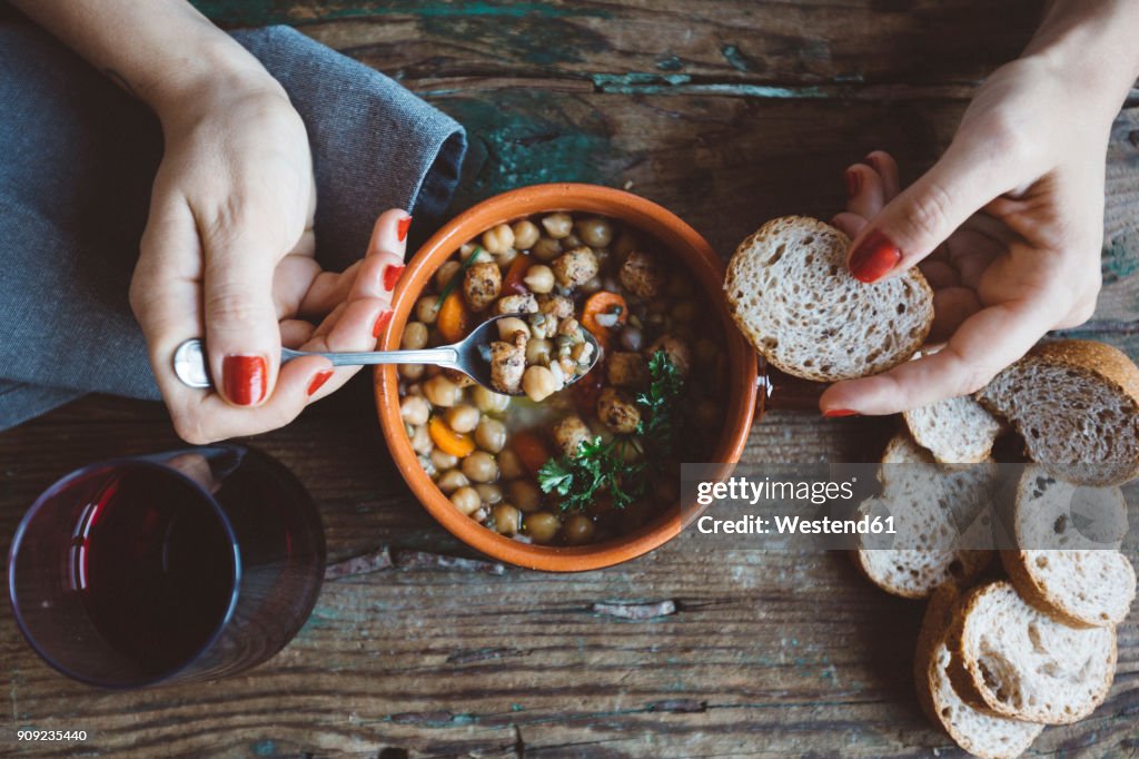 Woman eating Mediterranean soup with bread, close-up