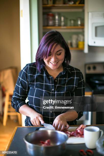 beautiful salvadorian millennial woman cooking in kitchen - el salvador woman stock pictures, royalty-free photos & images