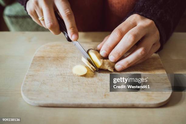 woman's hands cutting ginger on wooden board, close-up - ショウガ ストックフォトと画像
