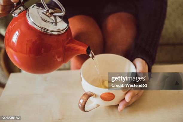 woman pouring water into tea cup with chopped fresh ginger, close-up - couchtisch stock-fotos und bilder