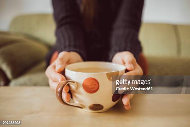 woman's hands holding tea cup, close-up - couchtisch stock-fotos und bilder