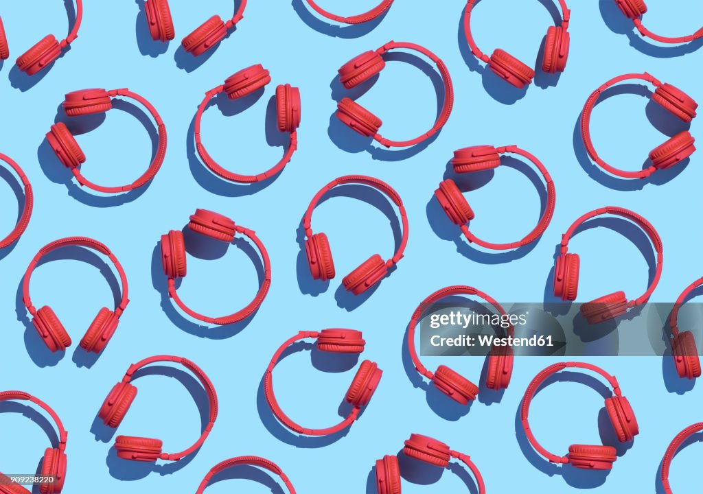 Collection of red wireless headphones on light blue background, 3D Rendering