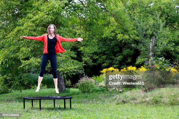 laughing woman jumping on trampoline in the garden - trampoline jump stock pictures, royalty-free photos & images