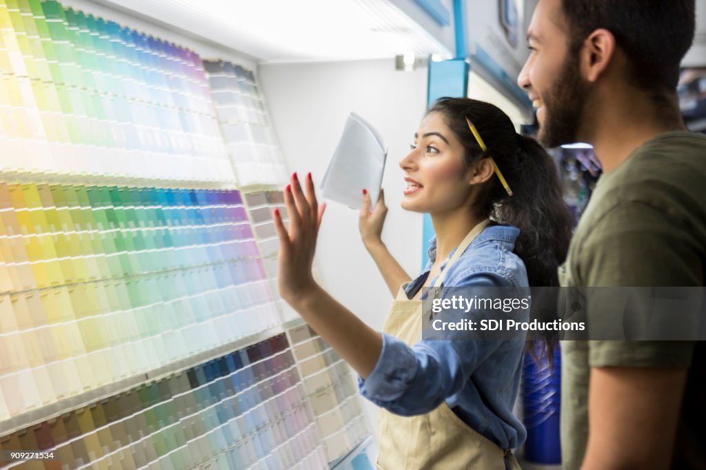 Paint store employee assists male customer