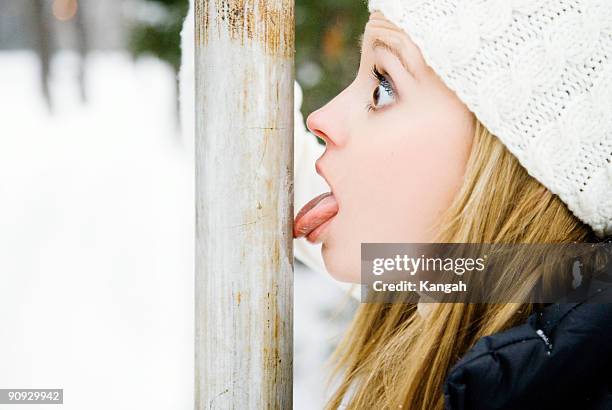 girl's tongue stuck to pole - vastzitten stockfoto's en -beelden