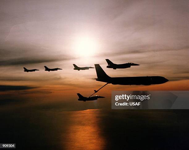 Five F-16 Fighting Falcon aircraft and a KC-135 Stratotanker aircraft are silhouetted against the sun during an aerial refueling operation over...