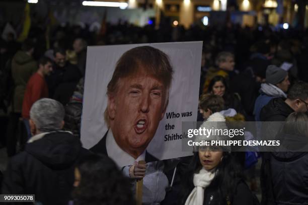 Protester holds up a banner with the image of the US president during a protest against his attendance to the upcoming World Economic Forum in Davos,...