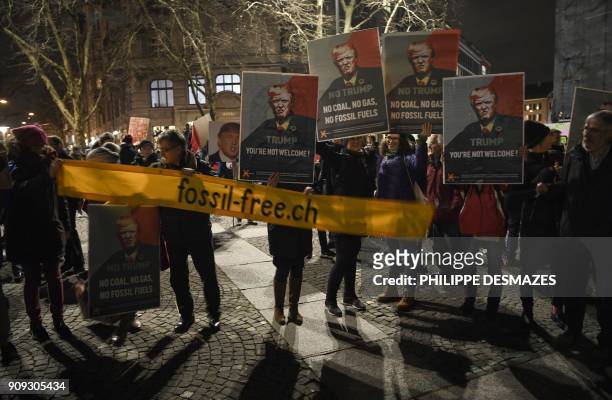 People hold up banners with the image of the US president as they protest against his attendance to the upcoming Davos World Economic Forum, on...